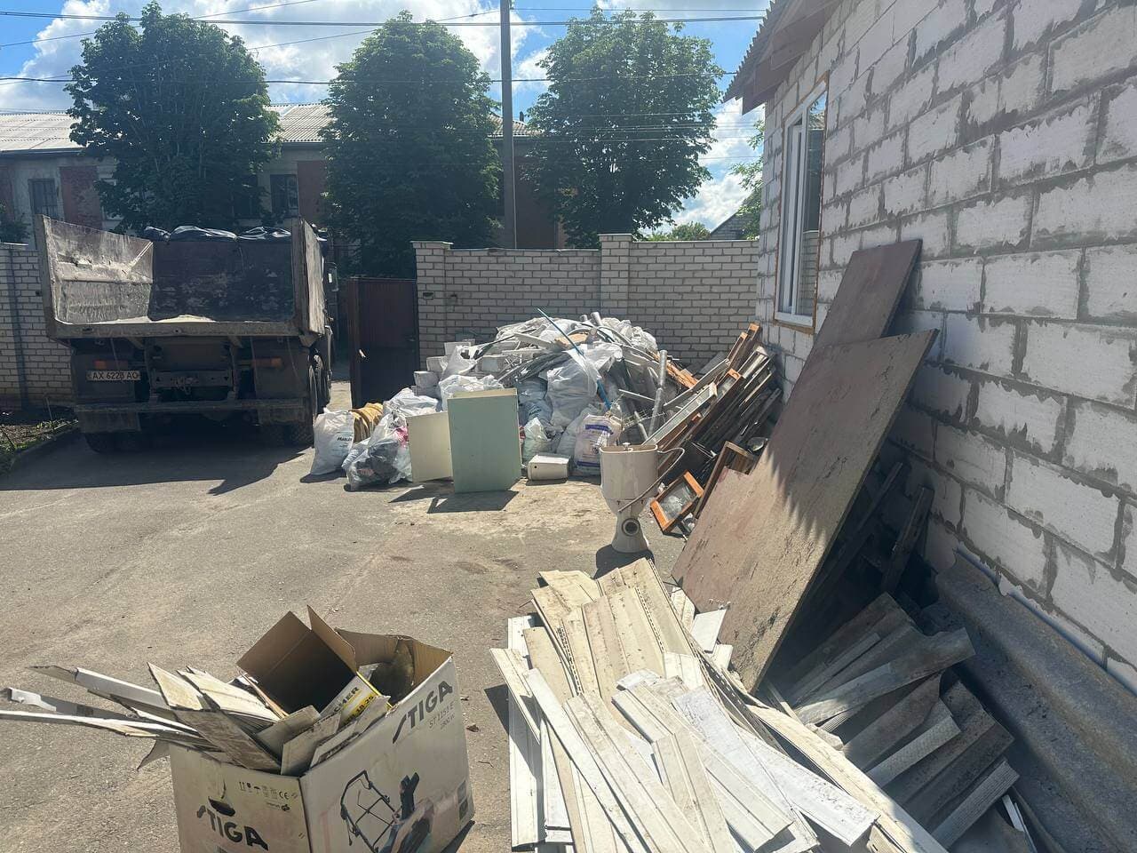 Будівельне сміття та віконні рами підготовлені до вивезення компанією «Вантаж Time». На подвір'ї припаркований КАМАЗ для навантаження відходів. Послуги демонтажу та вивезення сміття у Харкові.