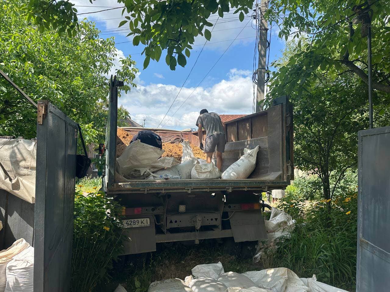 Робітник вантажить мішки у кузов КАМАЗу. Компанія «Вантаж Time» надає послуги перевезення сипучих матеріалів у Харкові.